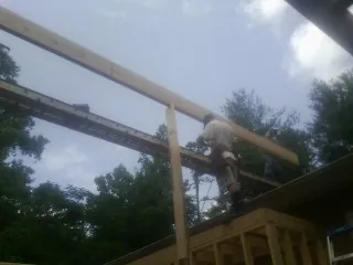 Carpenter setting a ridge beam over a new addition frame — Ice Dam Removal by Roofing Brothers in Ripplemead