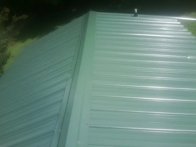 New green metal panels meeting at the ridge of a roof — Flat Roof Repair work by our crew in Ripplemead