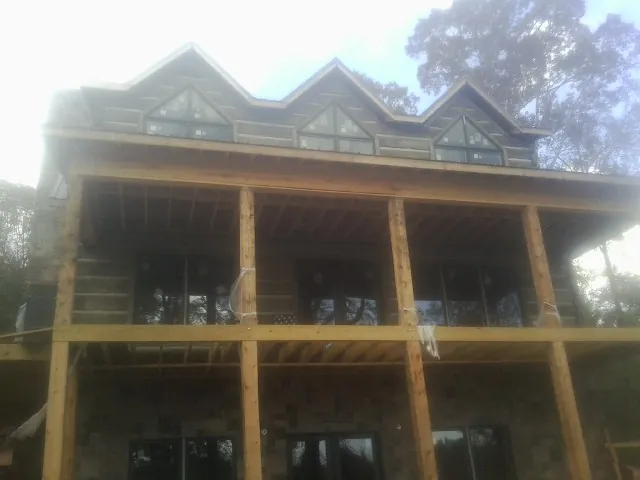Dormers and porch framing on a large log home under construction — Roof Coating work by our crew in Ripplemead