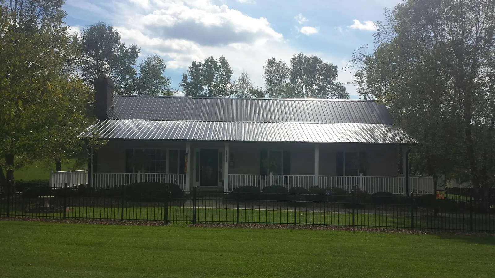 Gray metal roof on a brick ranch with a full width front porch — Gutter Guard Installation work by our crew in Ripplemead