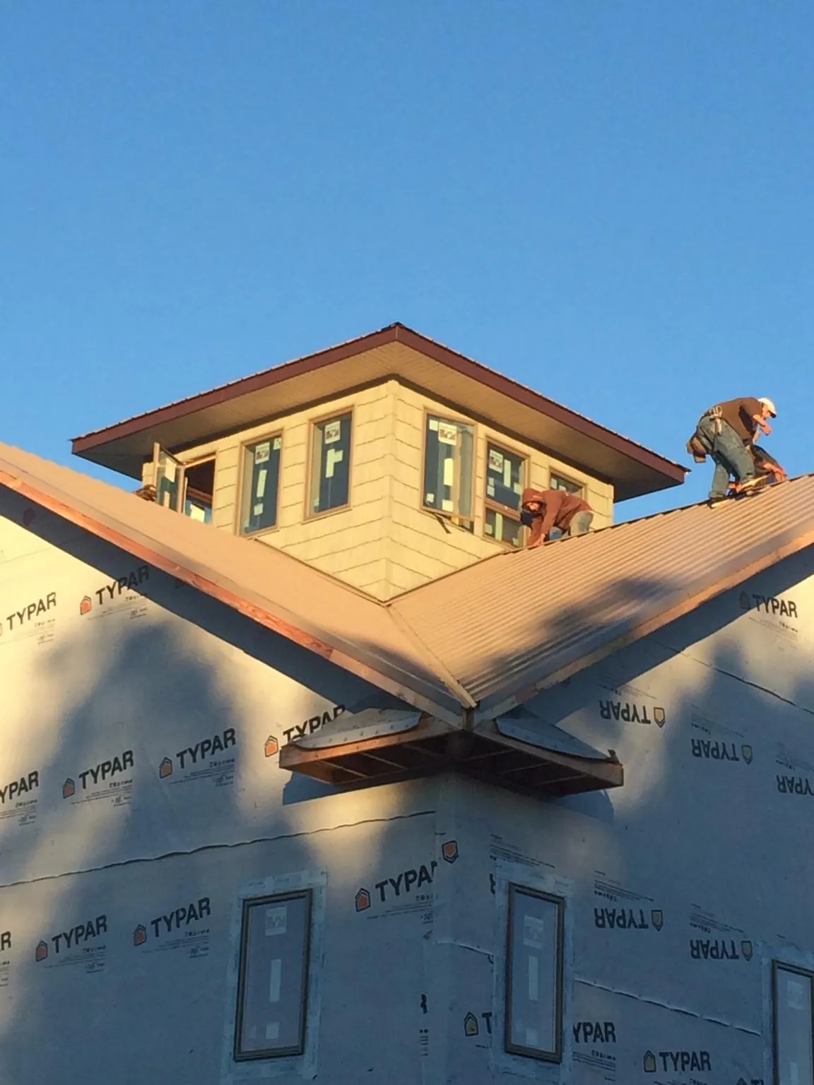 Roofers working around a rooftop cupola on a new metal roof at sunset — Roof Waterproofing in Ripplemead by Roofing Brothers